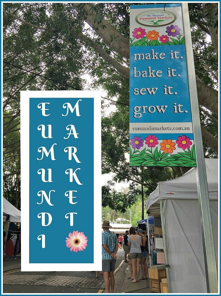 The Original Eumundi Market sign with market stalls under the canopy of big trees at Eumundi Markets Sunshine Coast